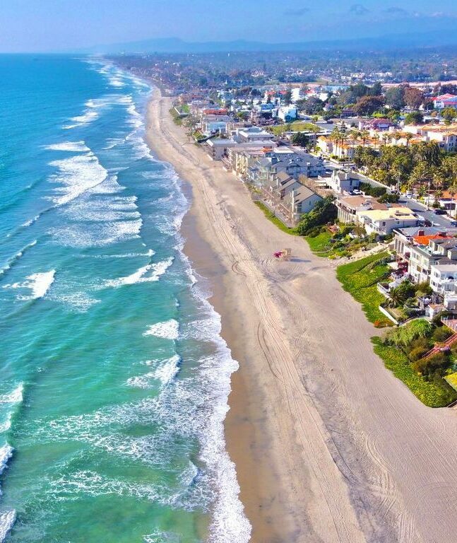 Beach shot from drone showing coast of California and homes along the sand