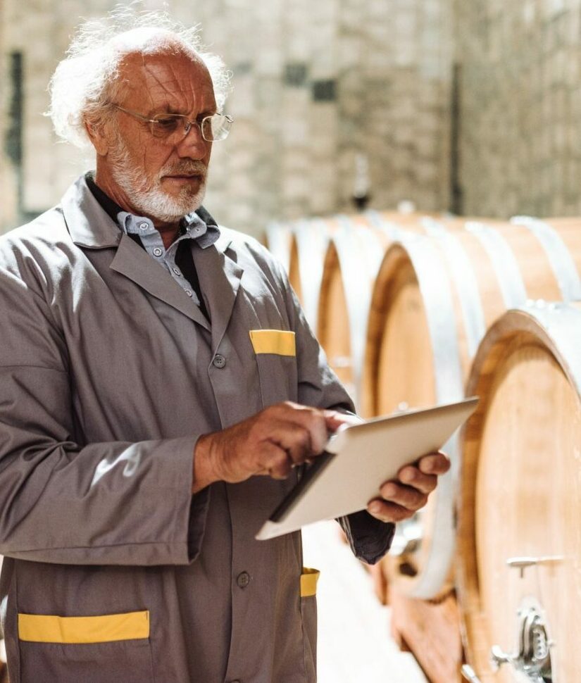 wine maker in a wine cellar with the tablet checking the quality