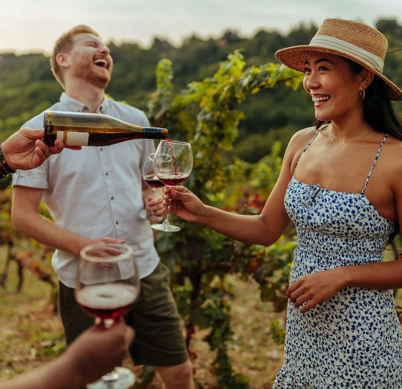 Man pouring glass of wine to his female friend in vineyard